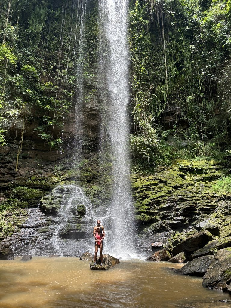 Traveler beneath a forest waterfall